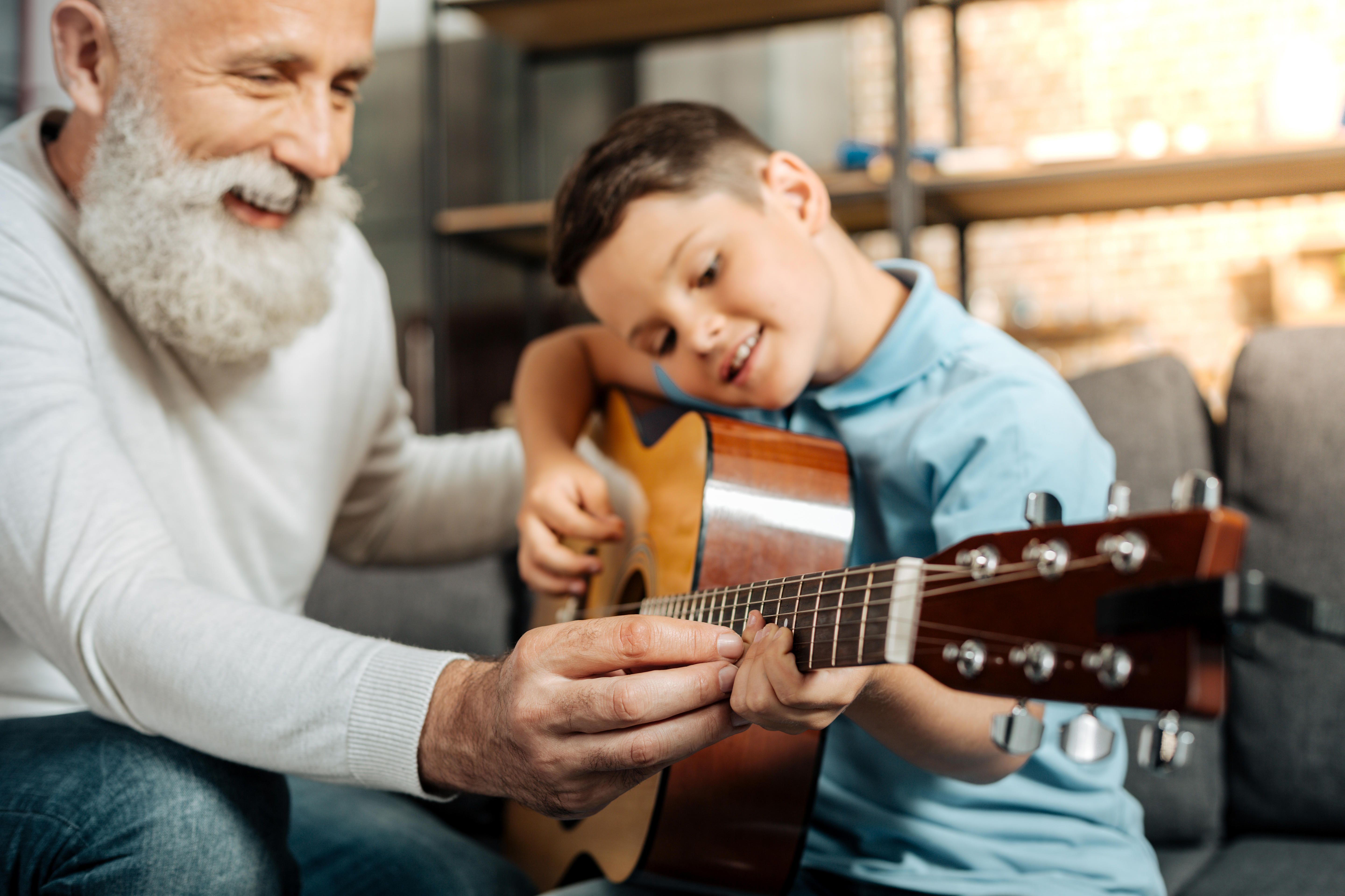 Grandfather teaching son to play the guitar.