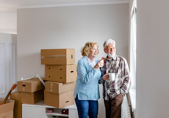 A senior couple is looking at the window in their new home on moving day